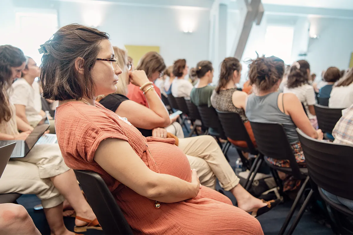 Femme enceinte assistant à une conférence dédiée à la santé de la femme et de la maternité.