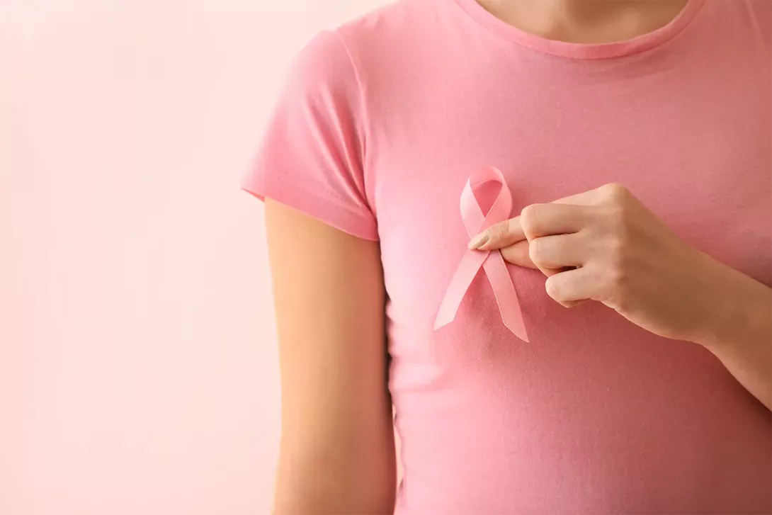 Ruban rose tenu sur un t-shirt, symbole de prévention du cancer du sein.